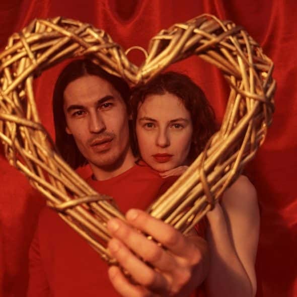 A man and woman holding a heart-shaped wood