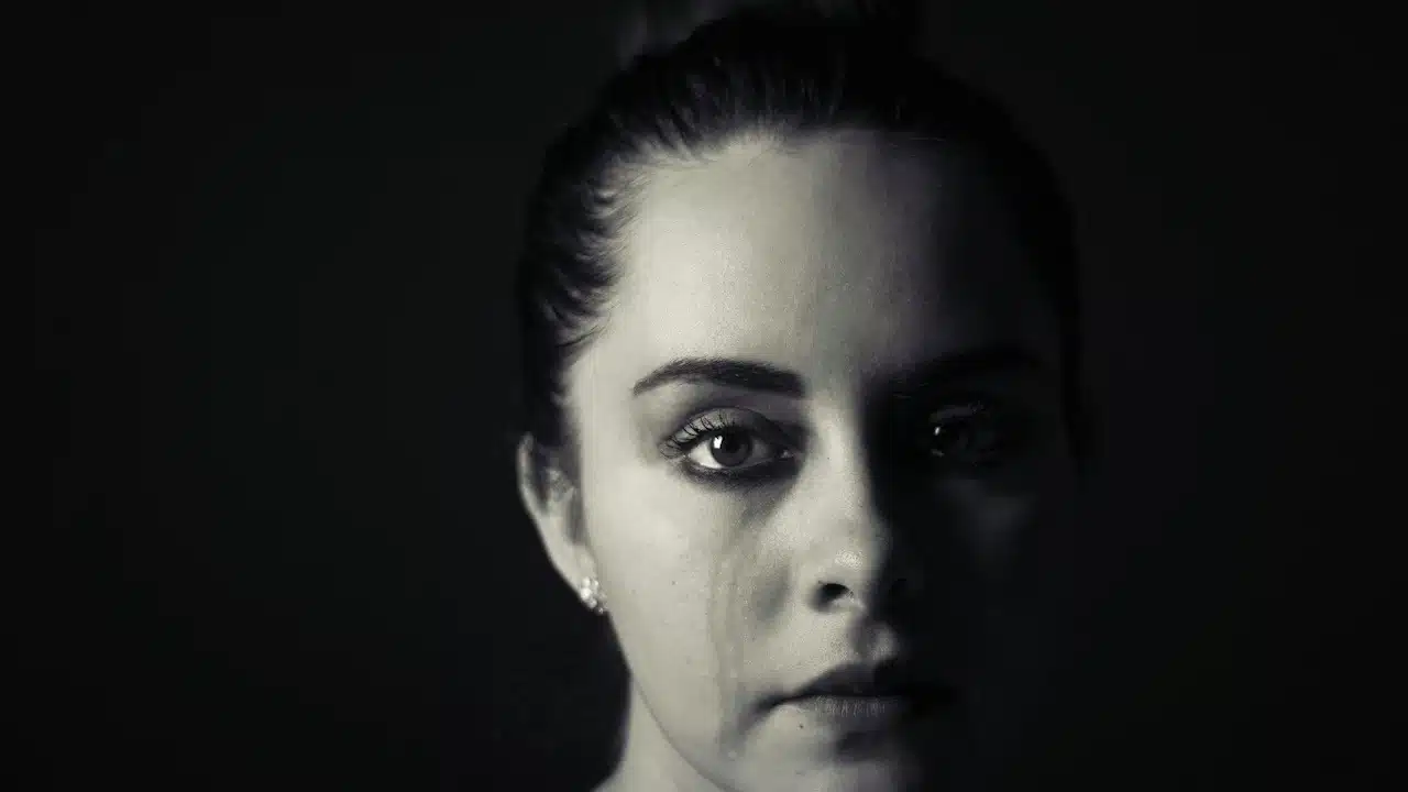 A woman is staring at the camera with tear stains on her cheek.