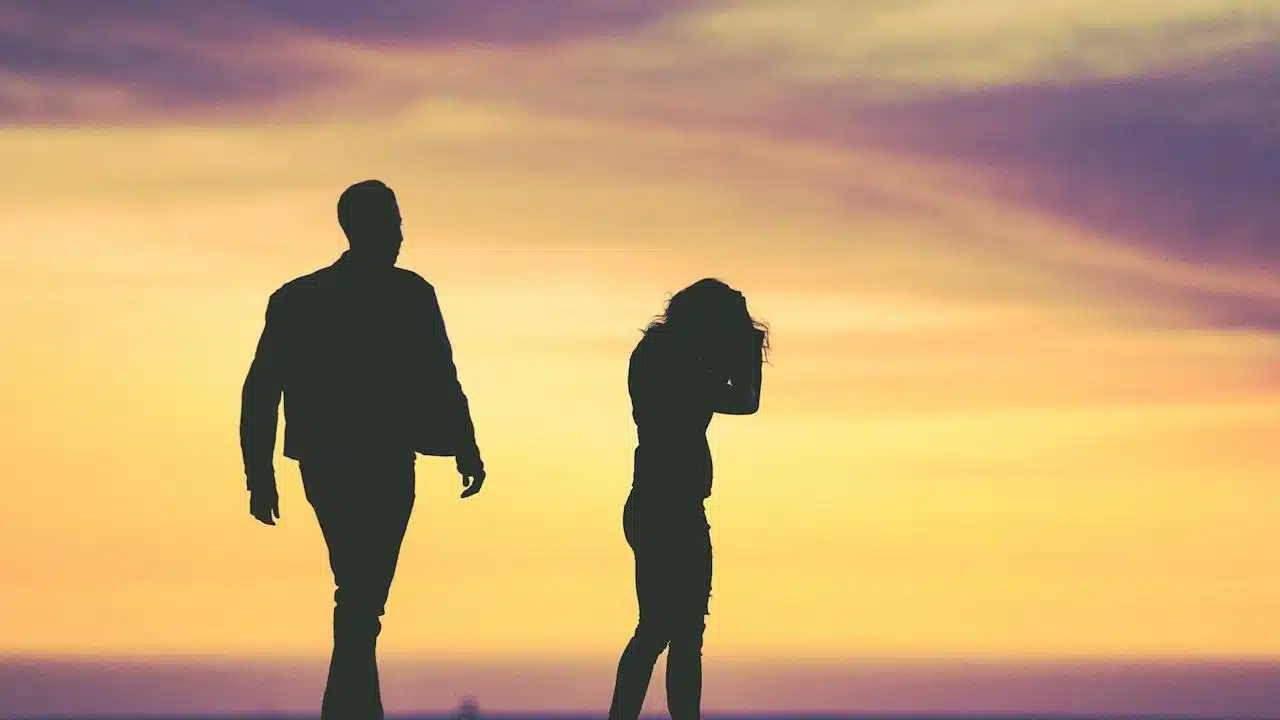 Silhouette of a man walking towards a woman who looks distressed.