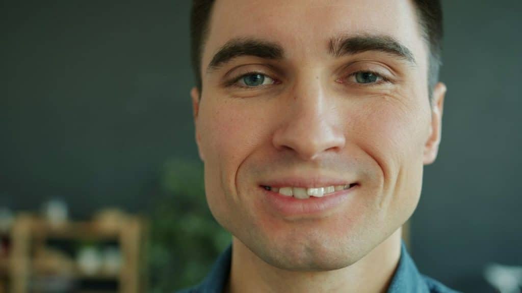 A close up portrait of a man with short dark hair smiling at the camera.
