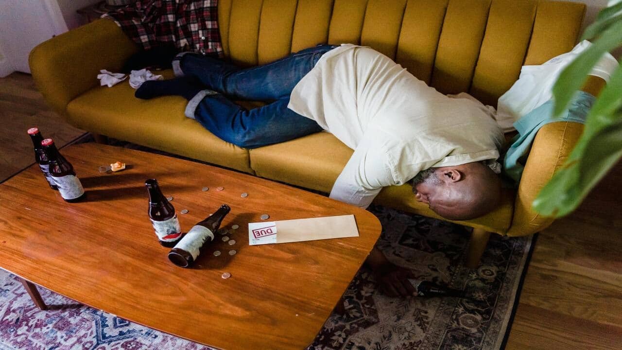 A man sleeping on the couch while drunk