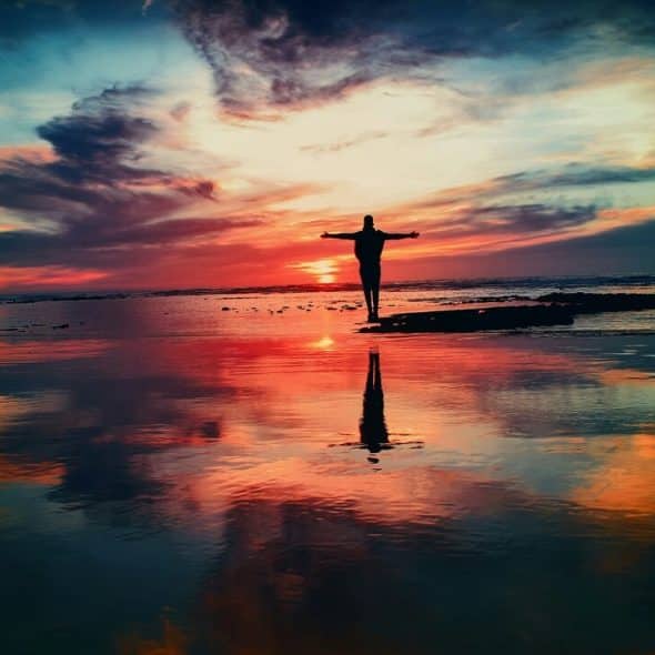 A man with his arms out by the ocean