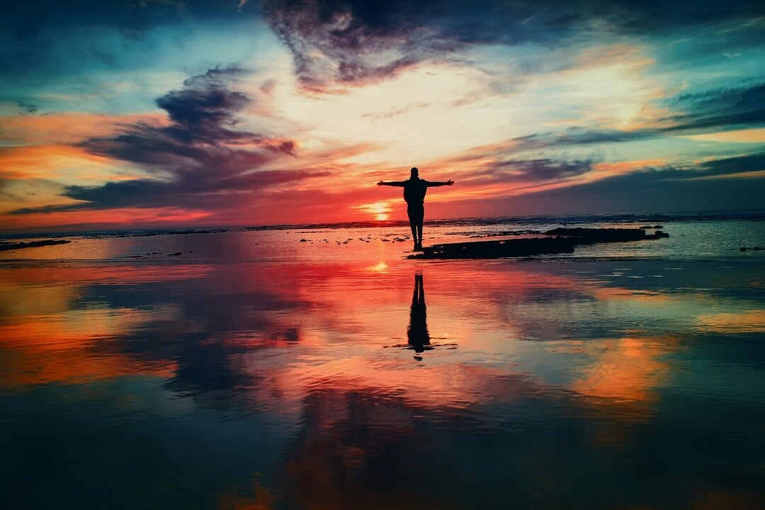 A man with his arms out by the ocean