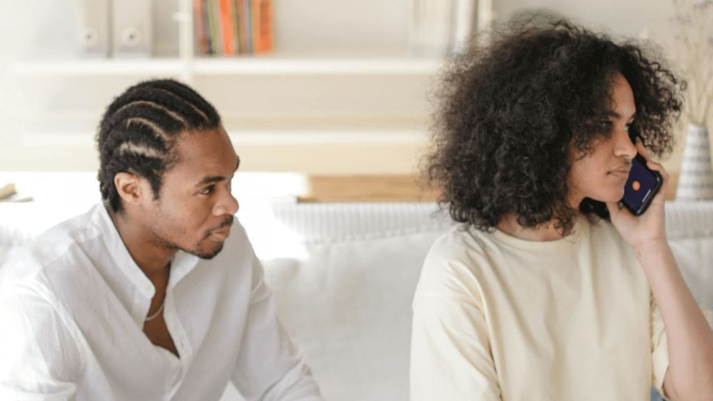 A woman talks on a phone while a man sits beside her looking at her.