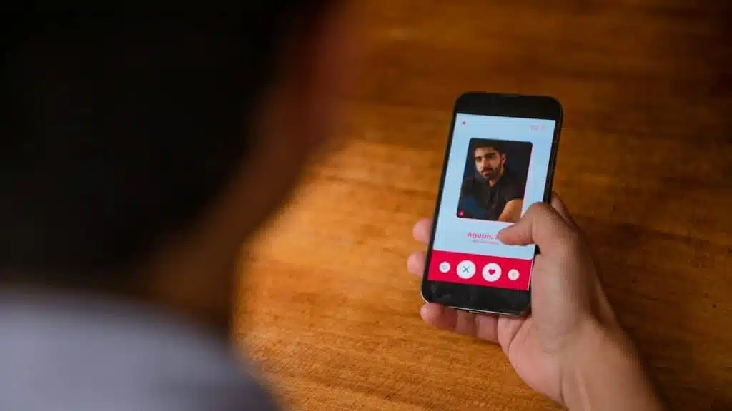 Over-the-shoulder view of a person holding a smartphone, viewing a dating app profile.