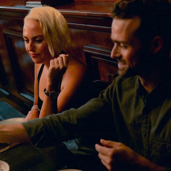 A couple sitting at a table on a date and having some food.
