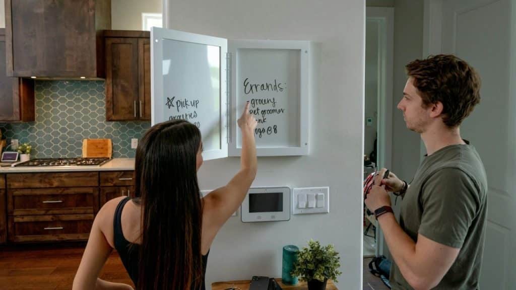 A woman points at a whiteboard while a man stands nearby holding a marker.