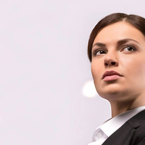 Low-angle view image of a beautiful young woman in formal wear keeping her arms crossed and looking away.