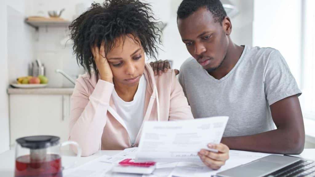 A man and woman sit together at a table while looking at a paper document.