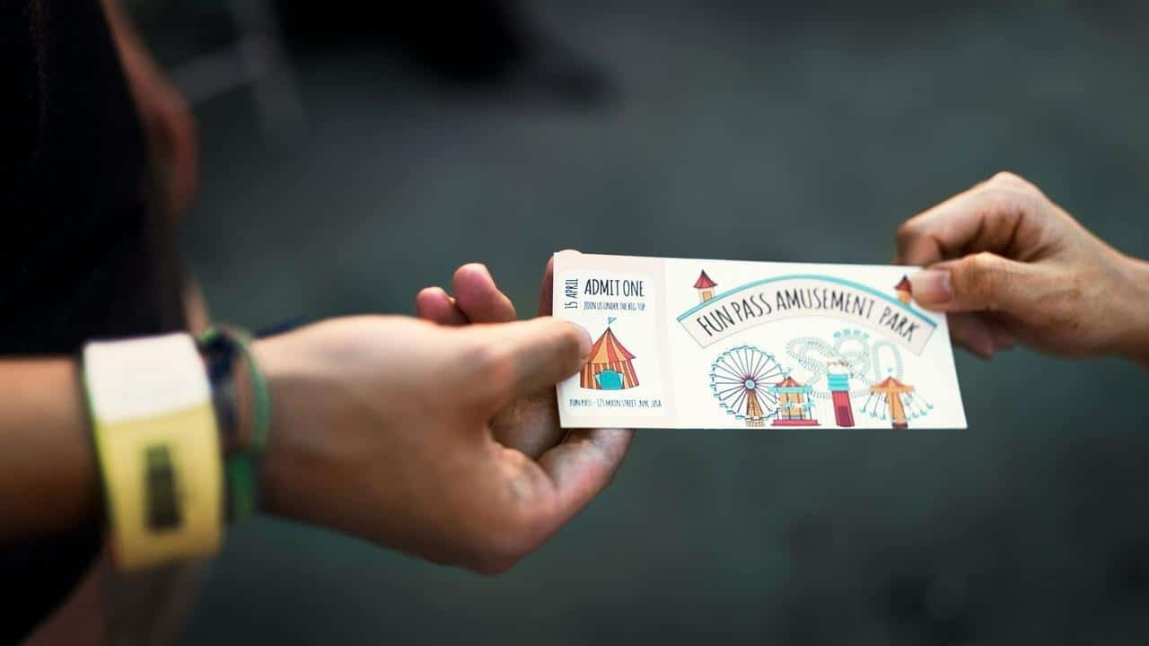 A person handing an amusement park ticket to another person.