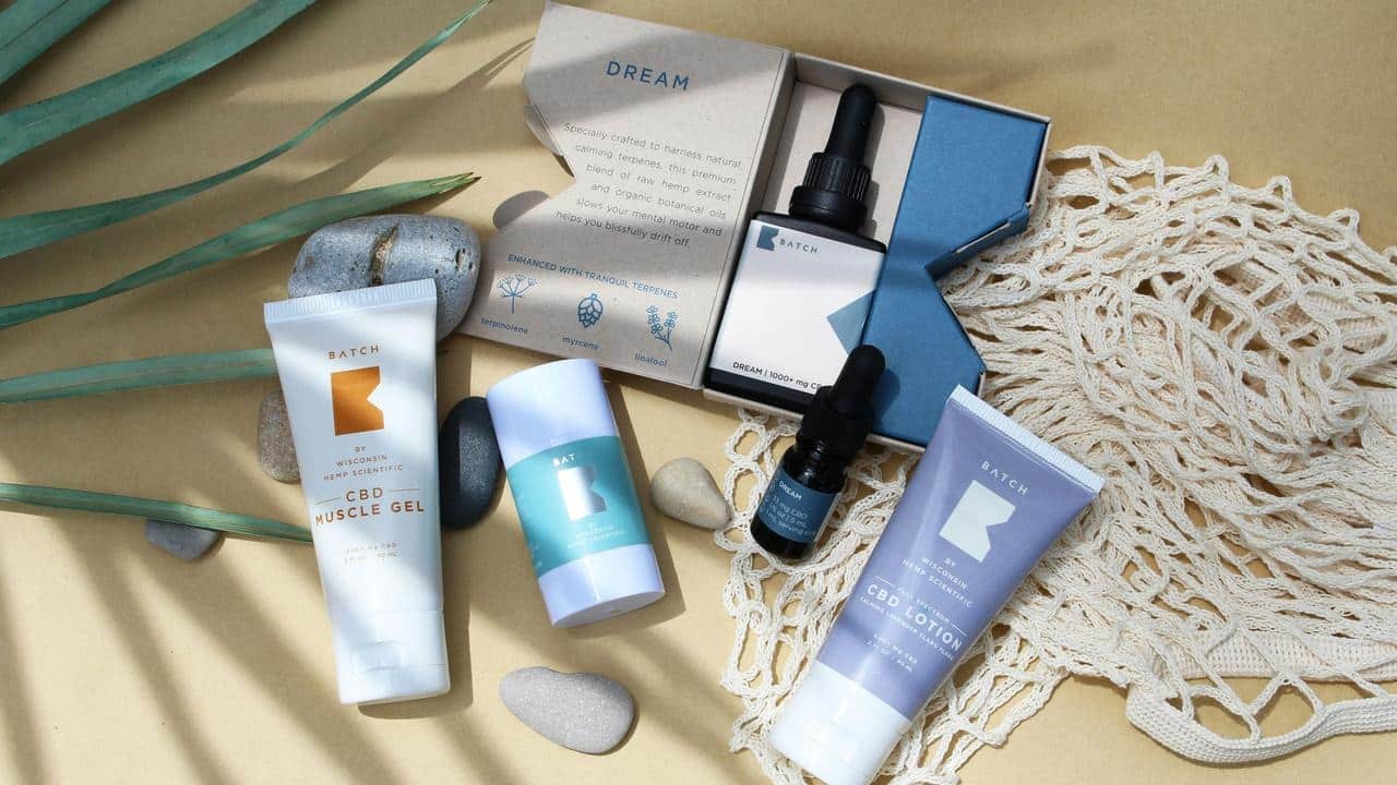 A flat lay of skincare products and dropper bottles arranged with stones and a net bag.