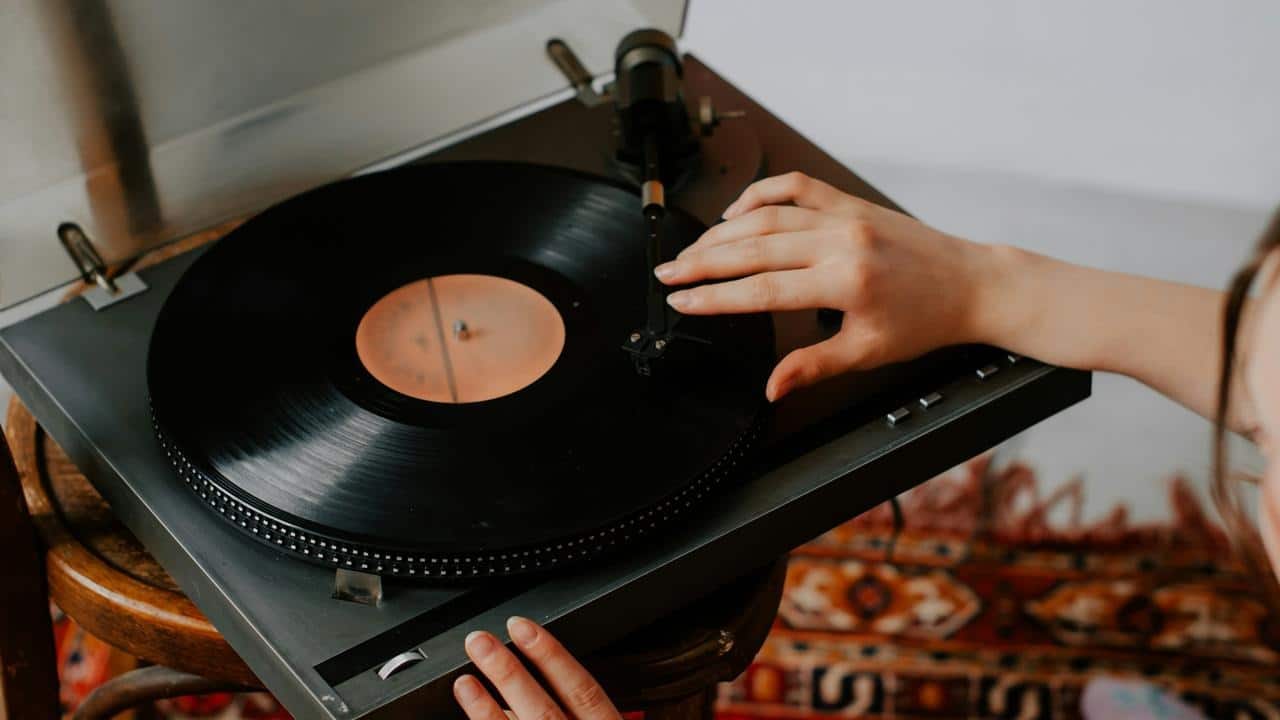 A hand placing the needle on a vinyl record player.