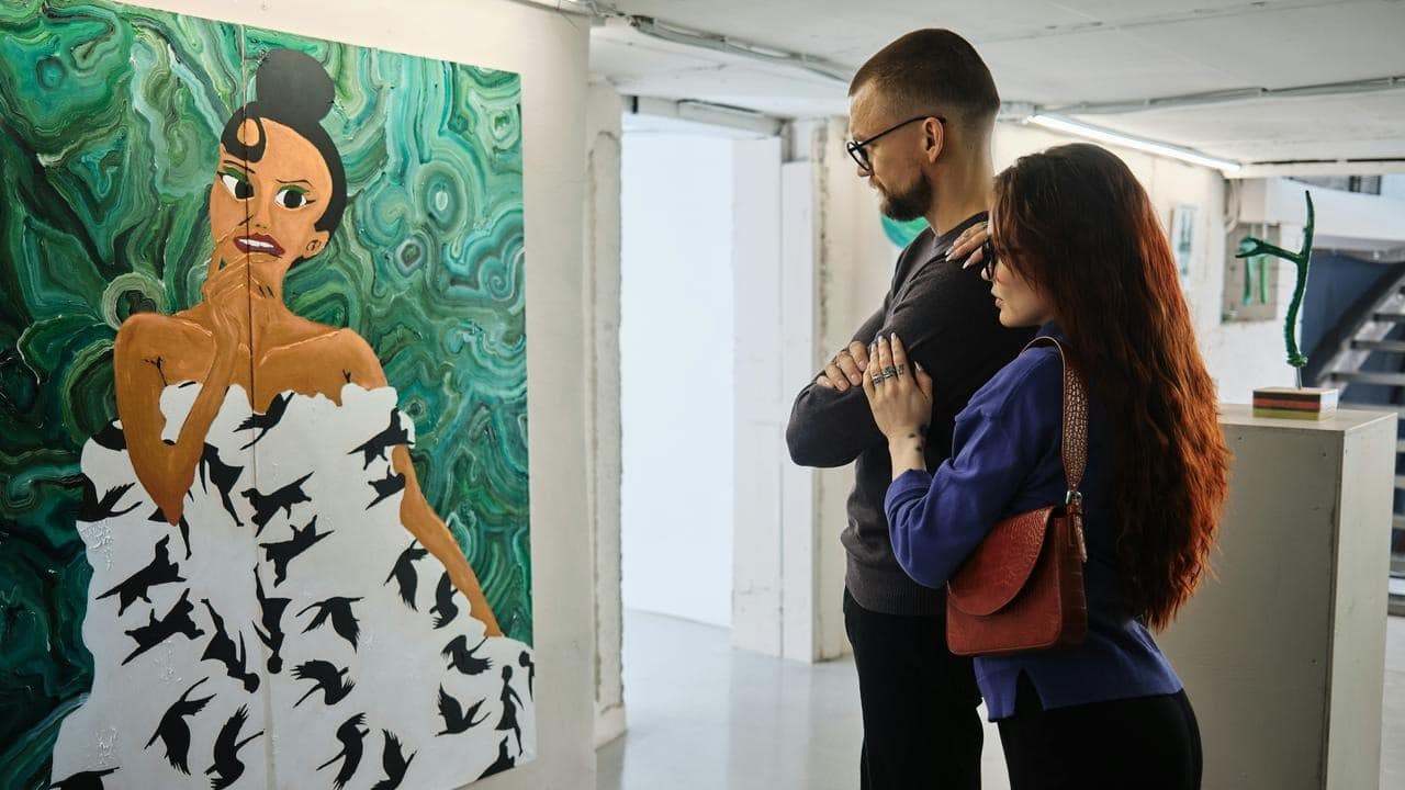 A couple viewing a colorful painting in a modern art gallery.