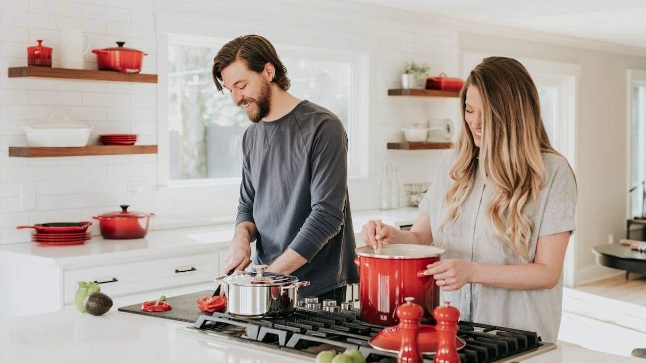 A man and a woman preparing food in their beautiful and tidy kitchen.
