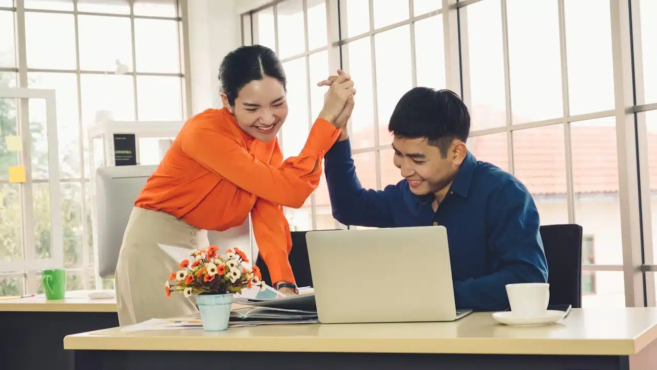 Successful businessman congratulate project success with colleague at modern workplace while having conversation on financial data report.