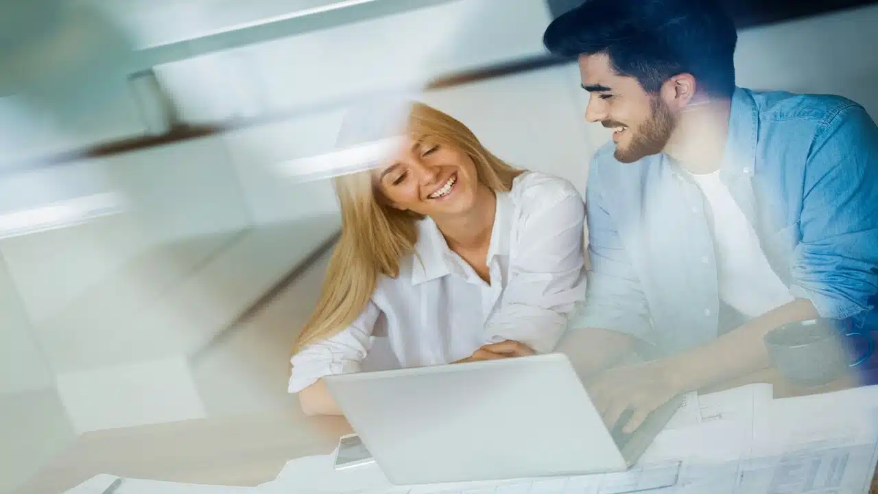 A couple smiling while looking at their bills 