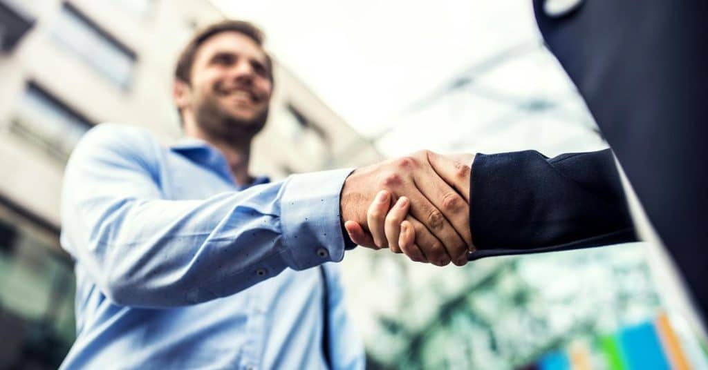 A close-up of two people shaking hands outdoors.