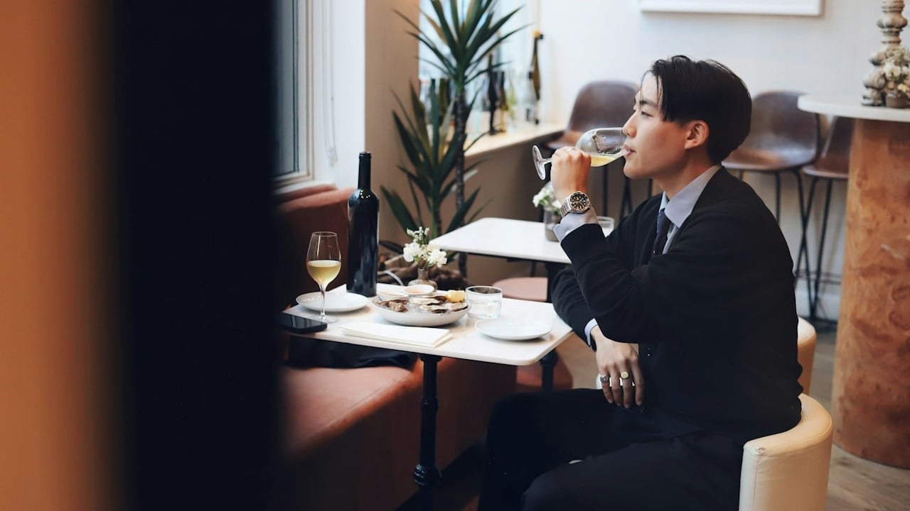 A man alone at a restaurant having a meal and drinking some wine.