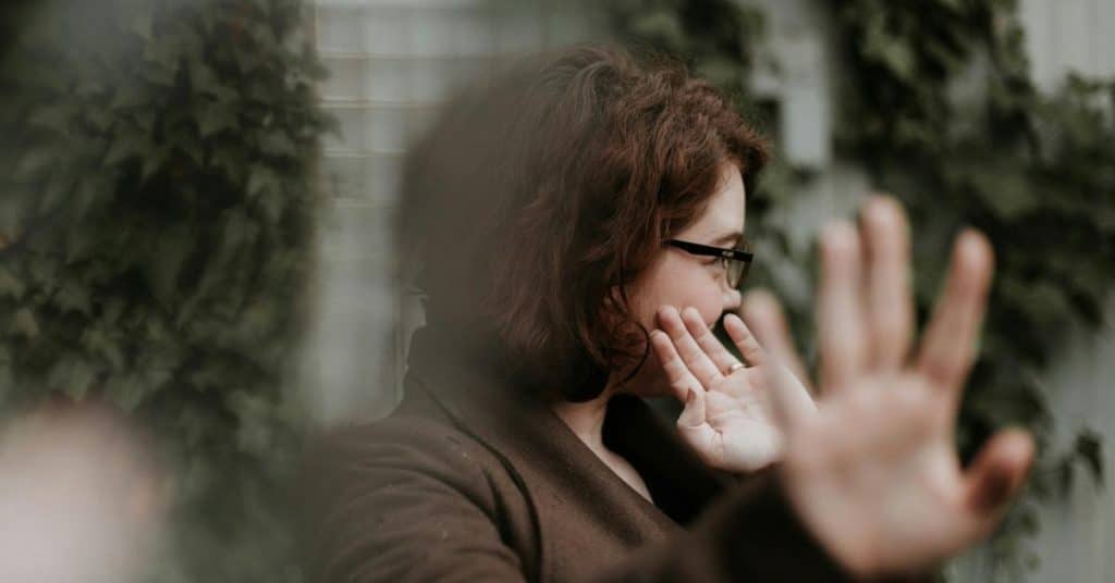 A woman turning away and raising her hand as if to block the view.