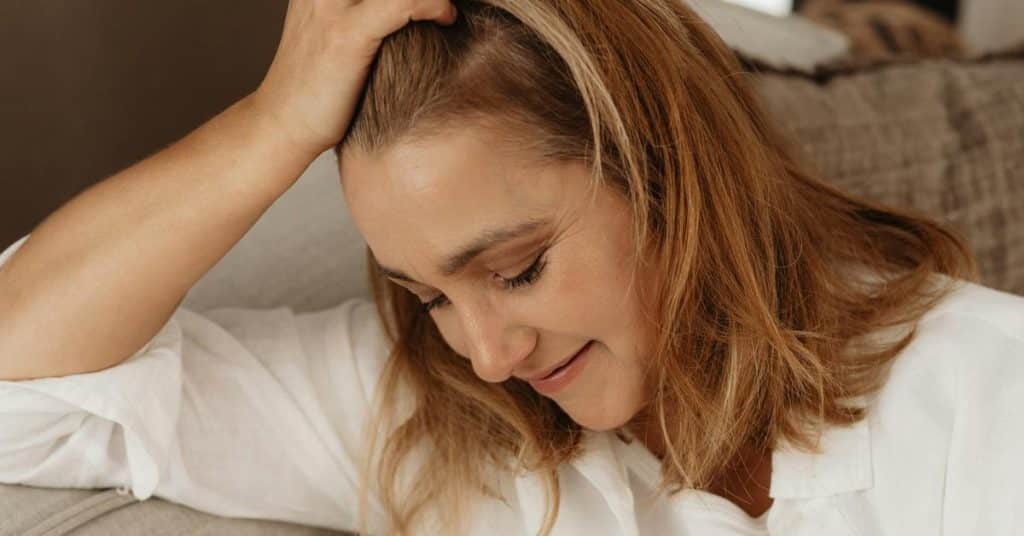 A woman resting her head on her hand with a gentle, reflective expression.