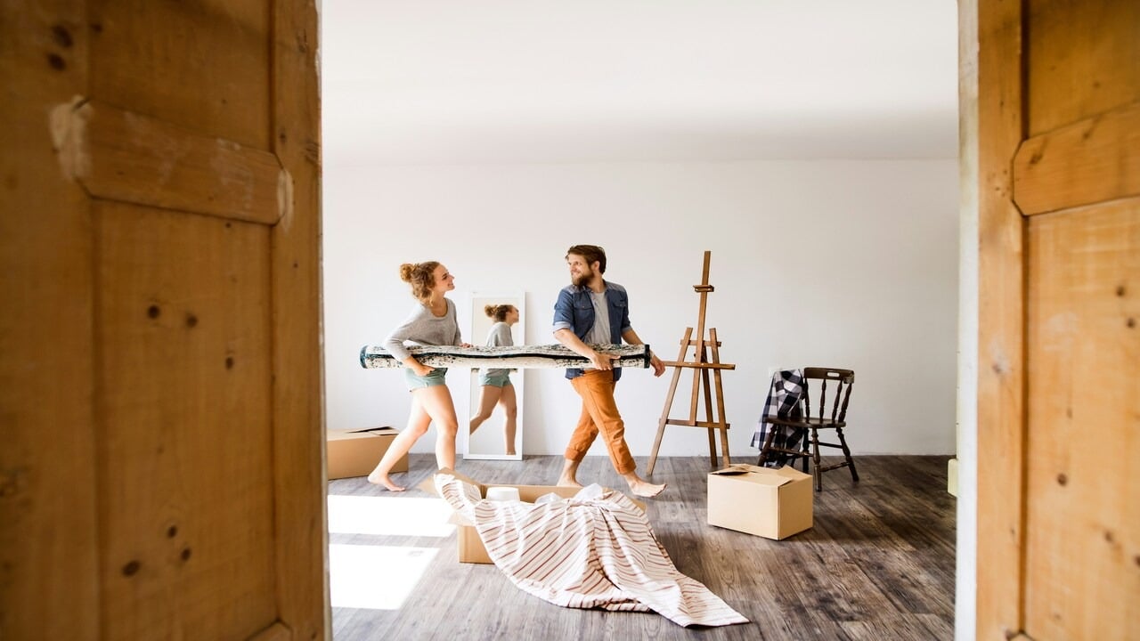 A couple carrying a carpet together
