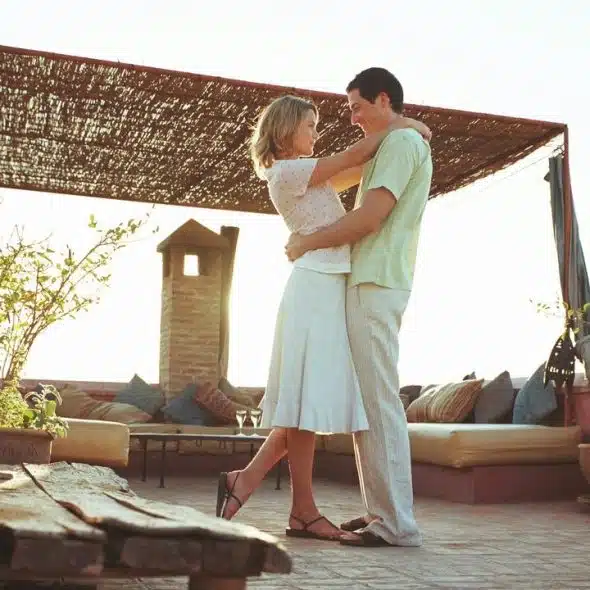 A couple embraces on a sunny rooftop terrace.