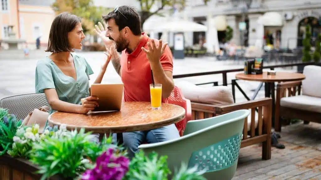 A couple sitting at an outdoor café table having an argument.