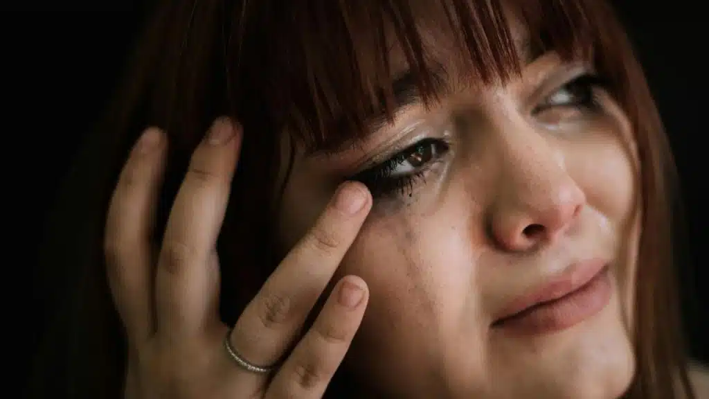 A close-up of a woman with tears and smudged makeup.