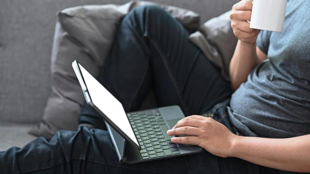 A person uses a laptop while holding a mug.
