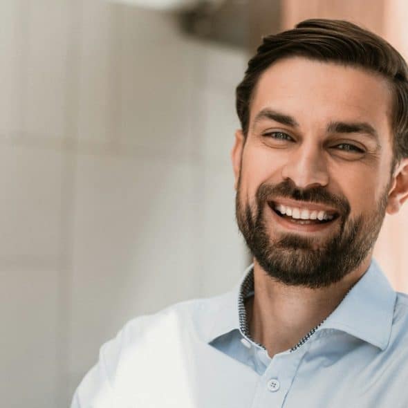 A bearded man smiling widely.