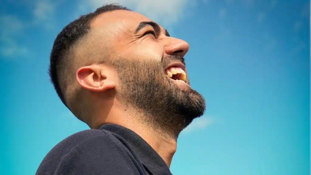 A bearded man laughing. 