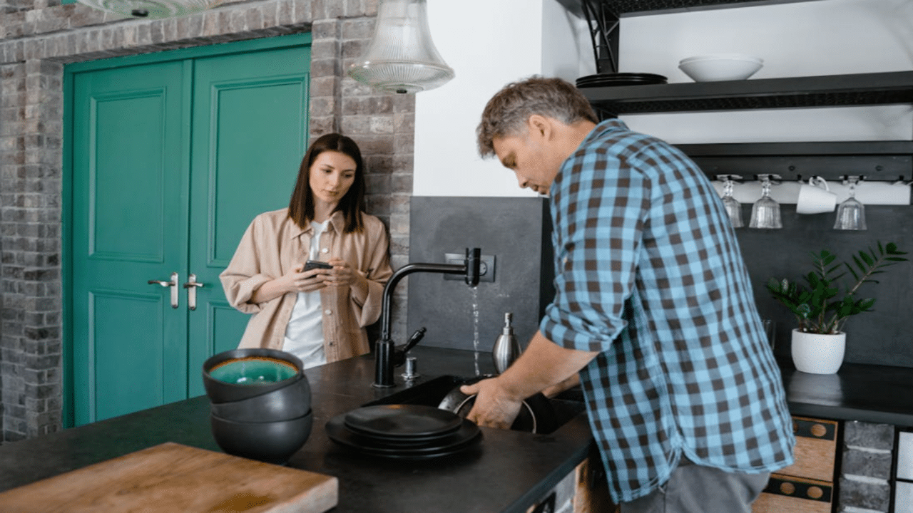 A woman watching her husband doing the dishes