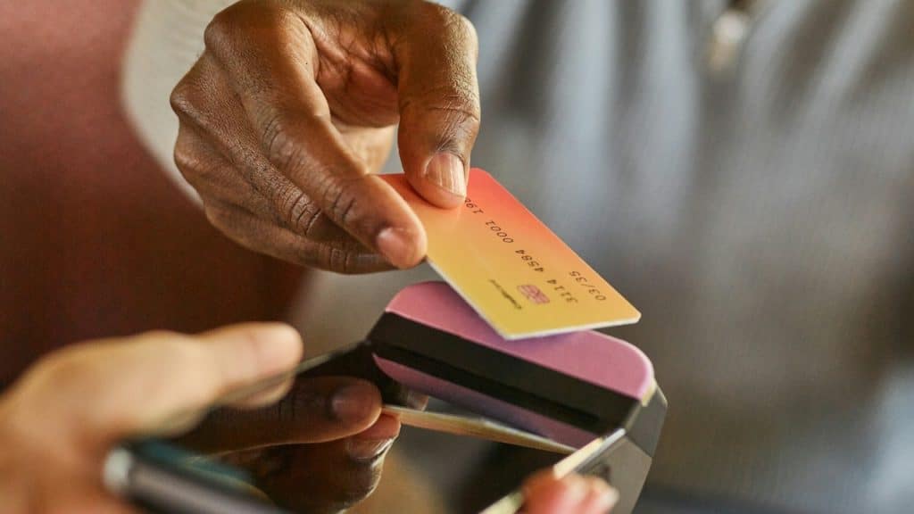 A man paying a bill with his debit card by tapping it on a cash machine.