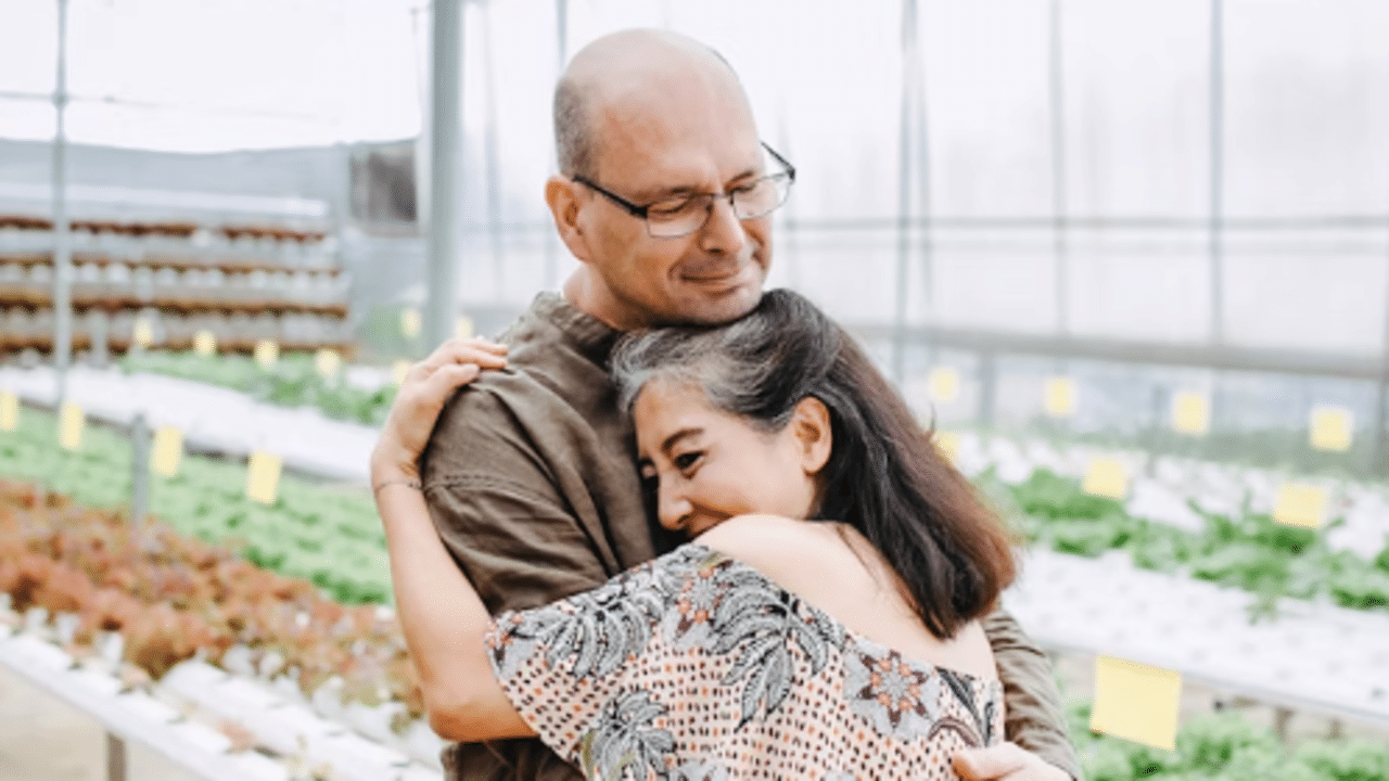 A couple hugging in a greenhouse