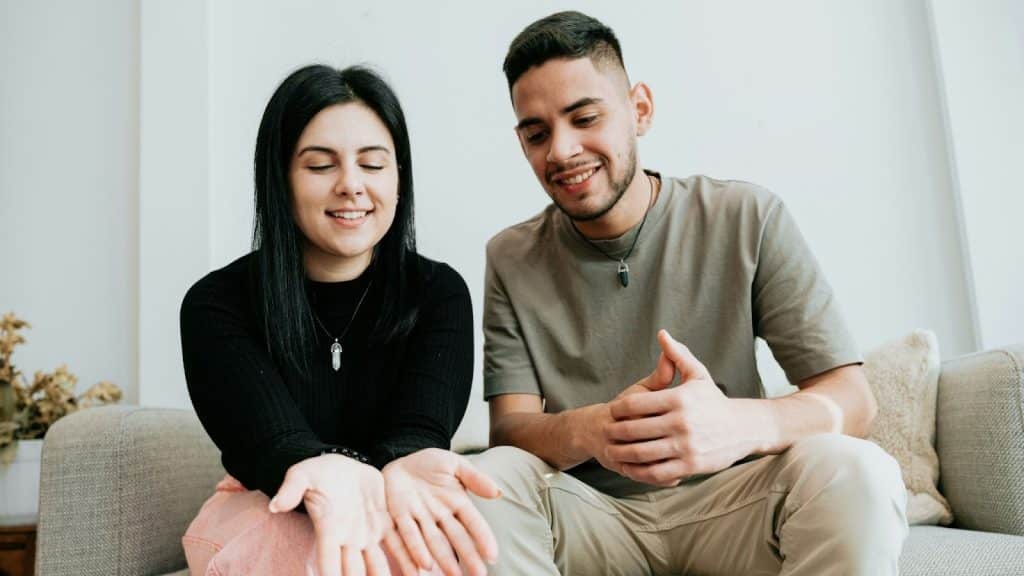 A woman explaining something to a man while they sit on a couch.
