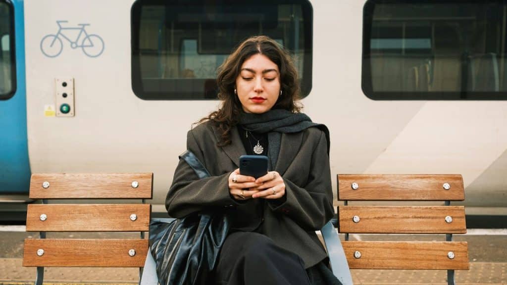 Woman using a phone while sitting on a seat in a subway.