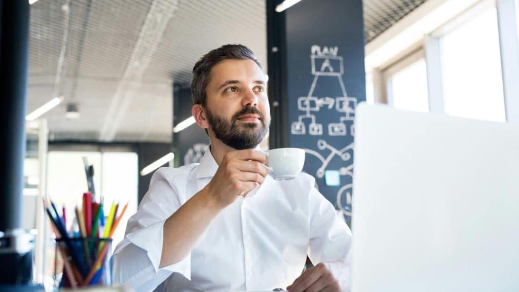 A man drinking coffee at his desk.