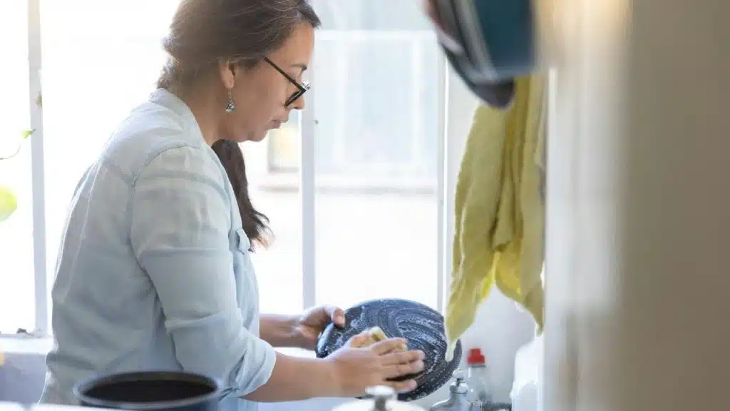 A woman washing dishes at a kitchen sink.
