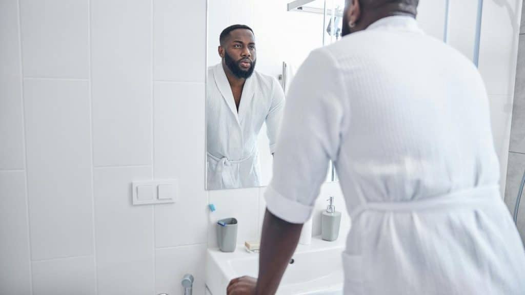 A father looking at himself in the bathroom mirror.