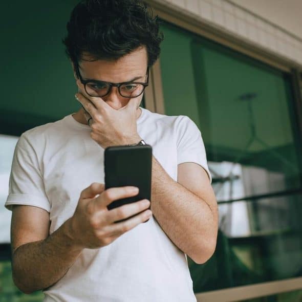 A man looks worried while reading something on his phone.