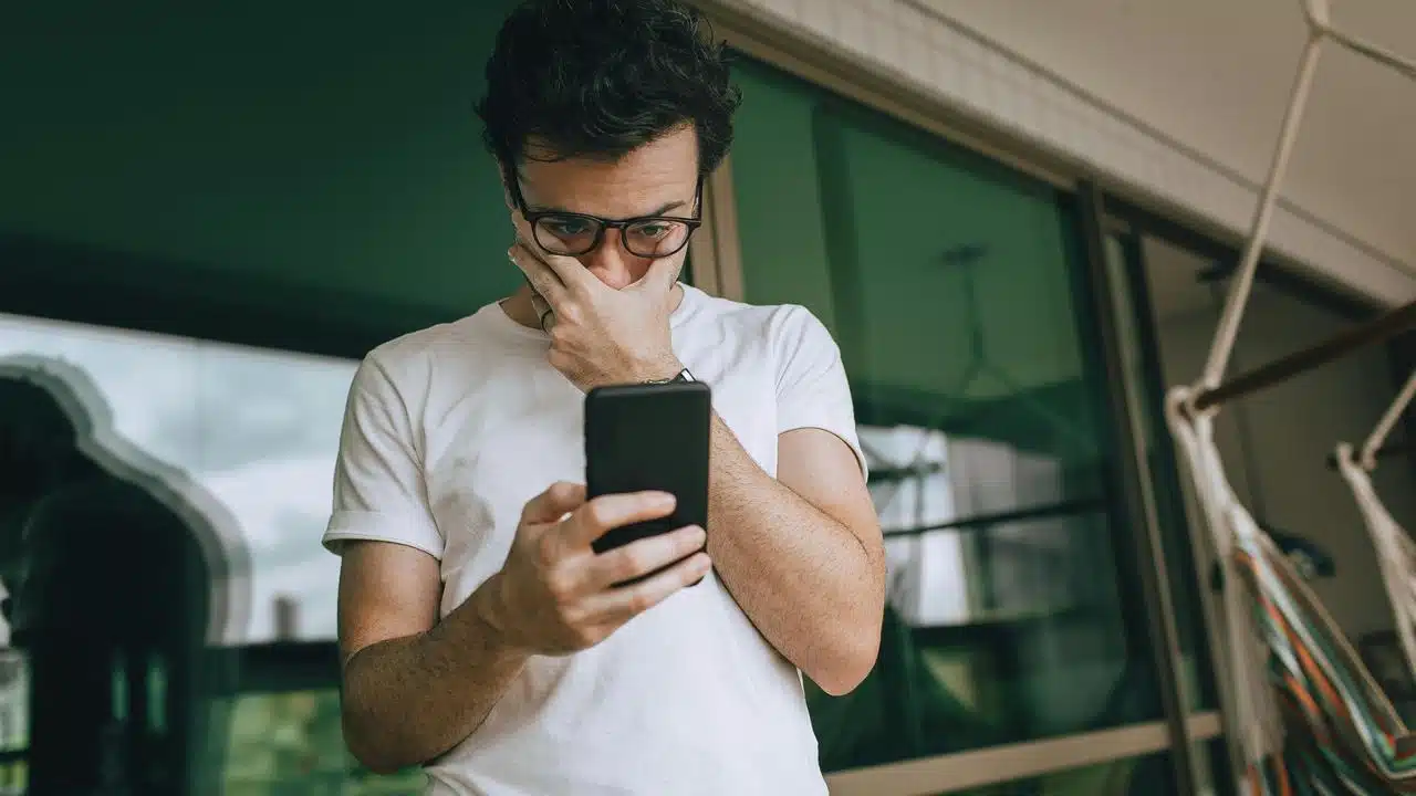 A man looks worried while reading something on his phone.