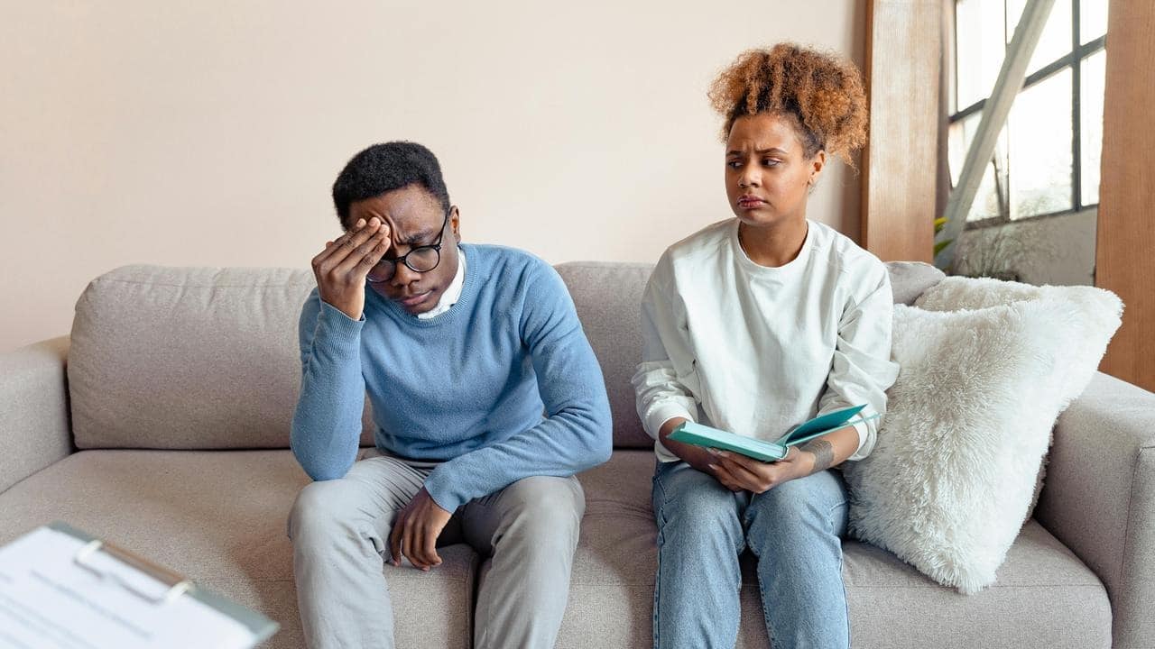 A distressed couple sitting on a couch.