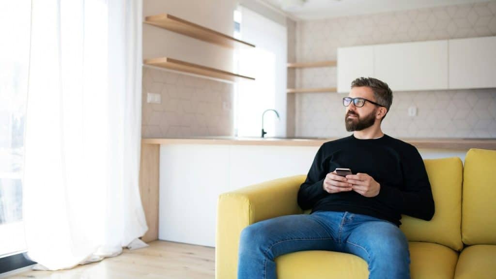 A man sitting on sofa holding his phone