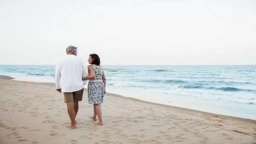 A mature couple walking down by the beach