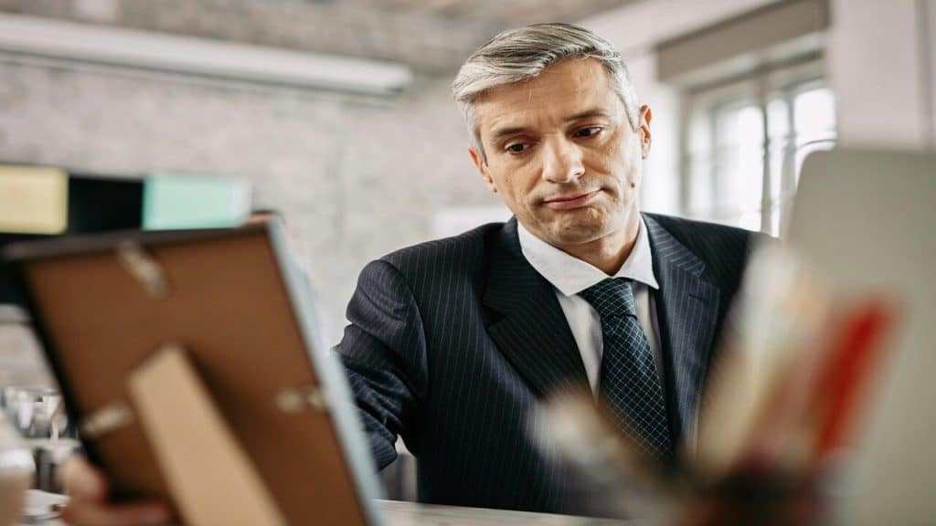 A sad mature man looking at a picture frame