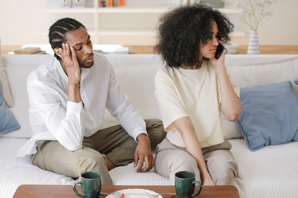 Couple on couch one on phone ignoring