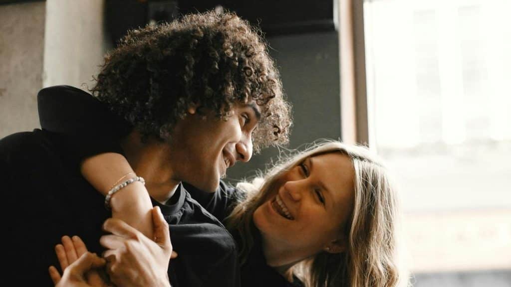A couple smiling and embracing each other indoors.