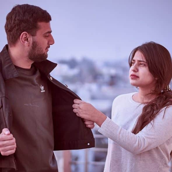 A woman grabbing the jacket of her boyfriend, who is trying to move away.