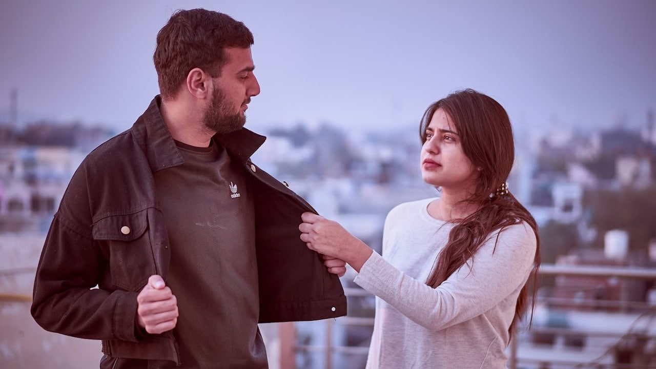 A woman grabbing the jacket of her boyfriend, who is trying to move away.