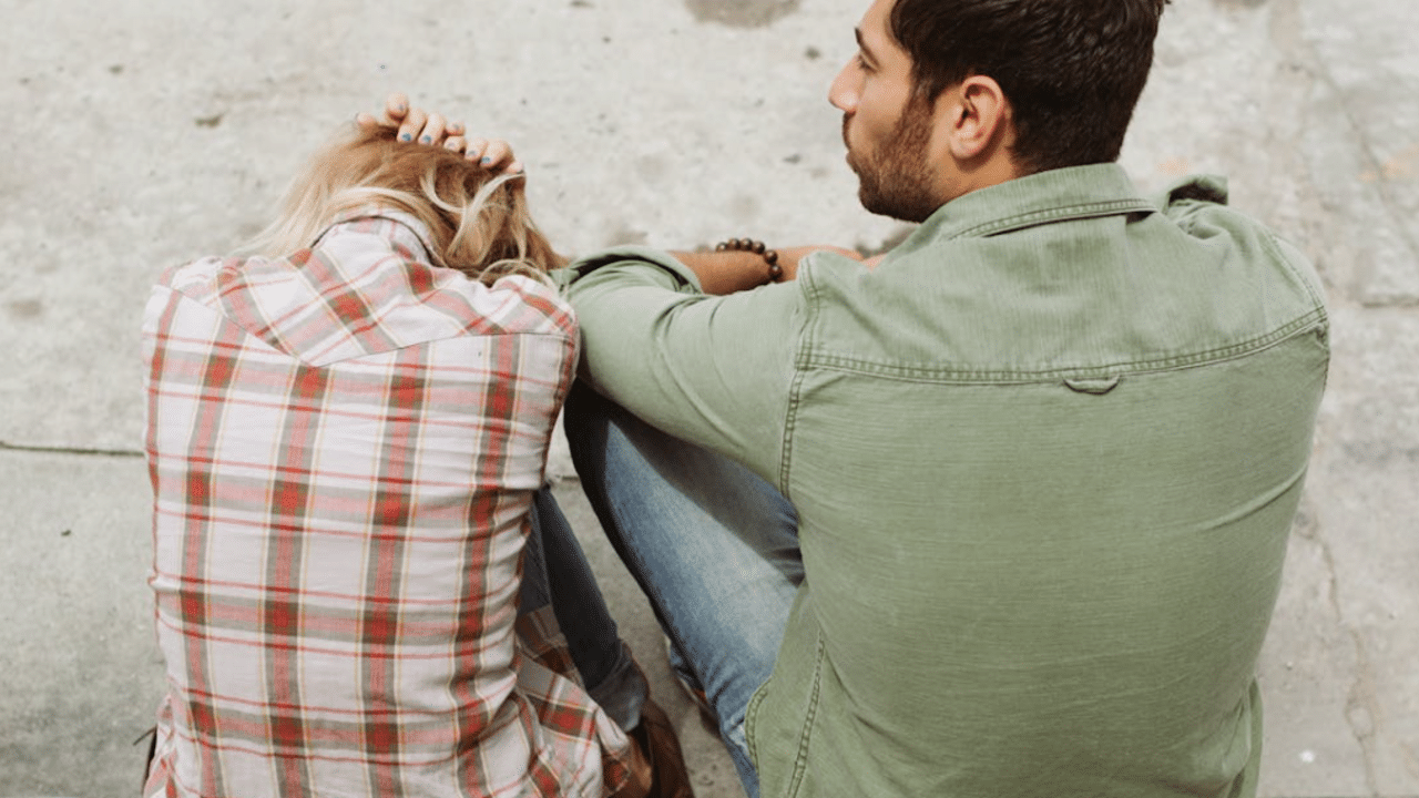A couple sitting on a sidewalk